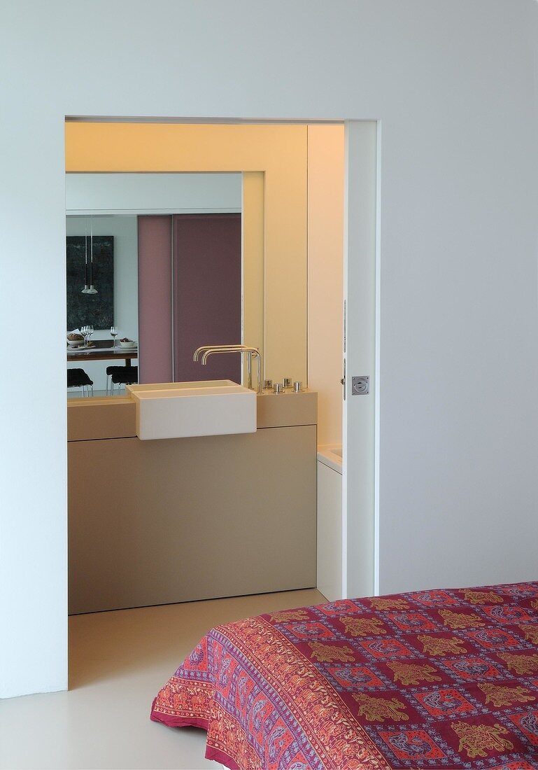 View of bedroom overlooking bathroom with sink and sliding door