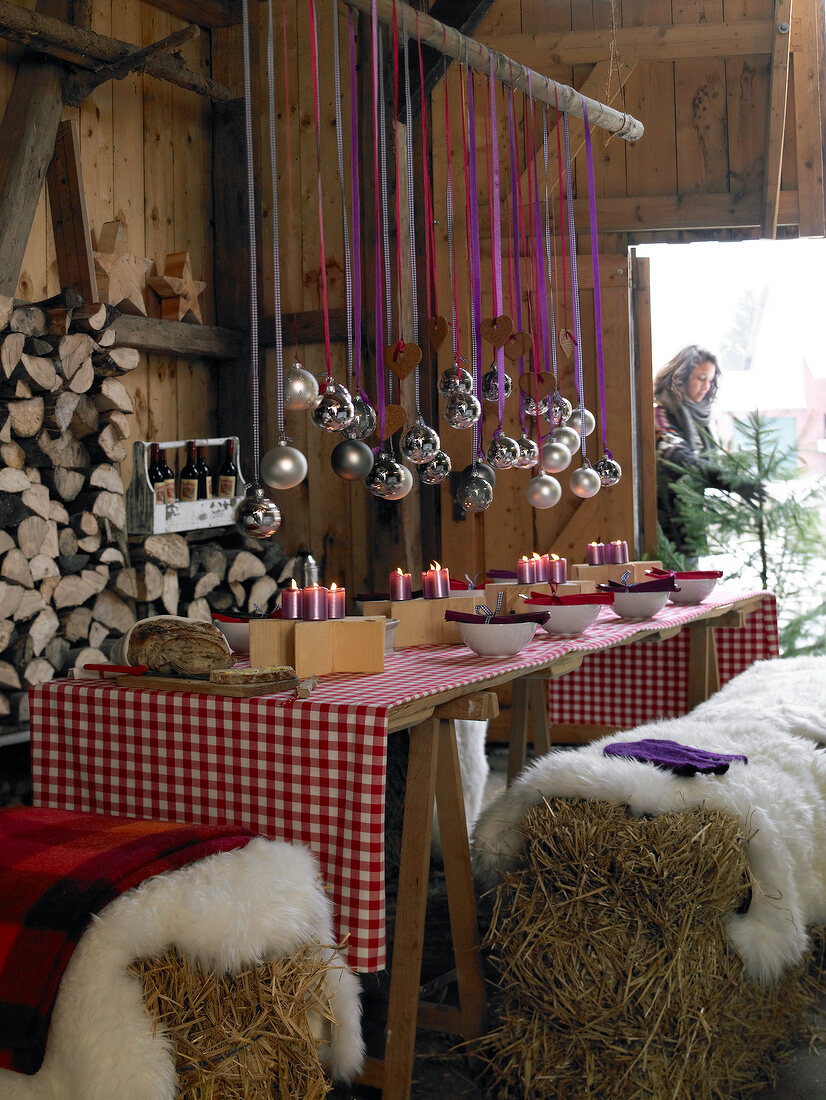 Table decorated with baubles and candles in barn for Christmas