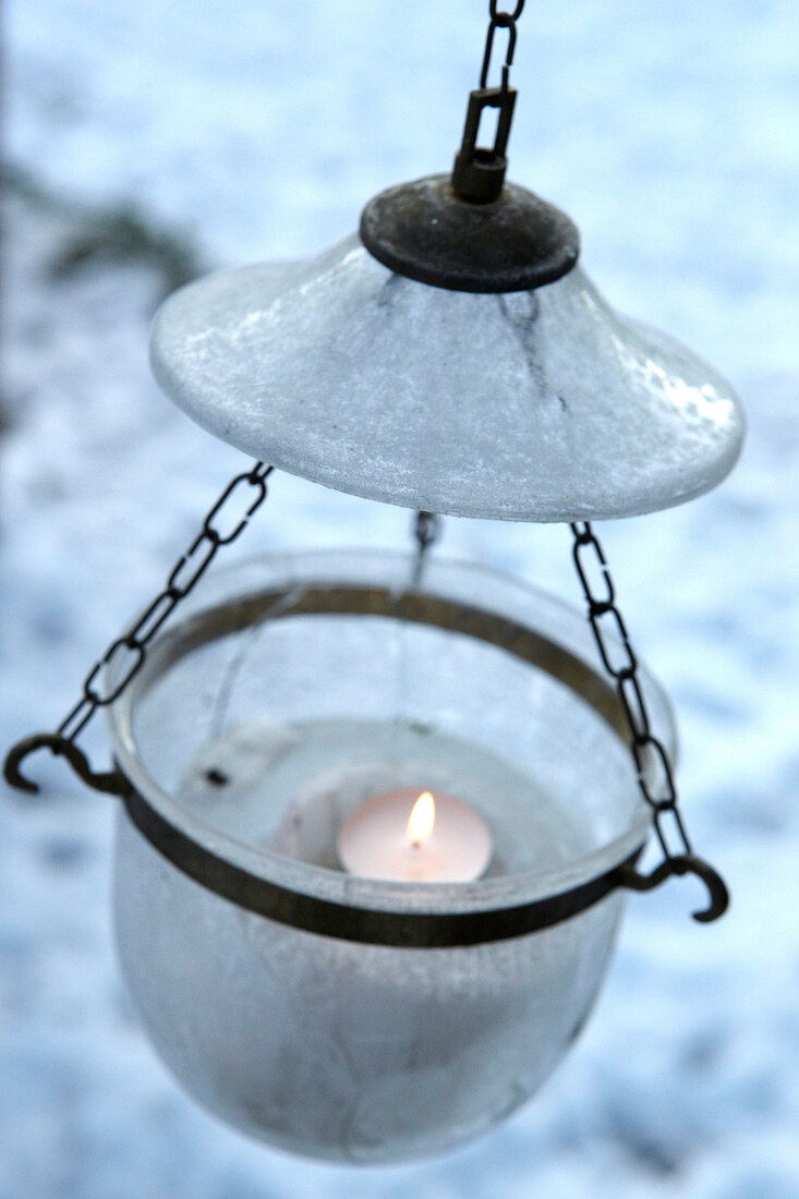 Lit candle in glass, hanging