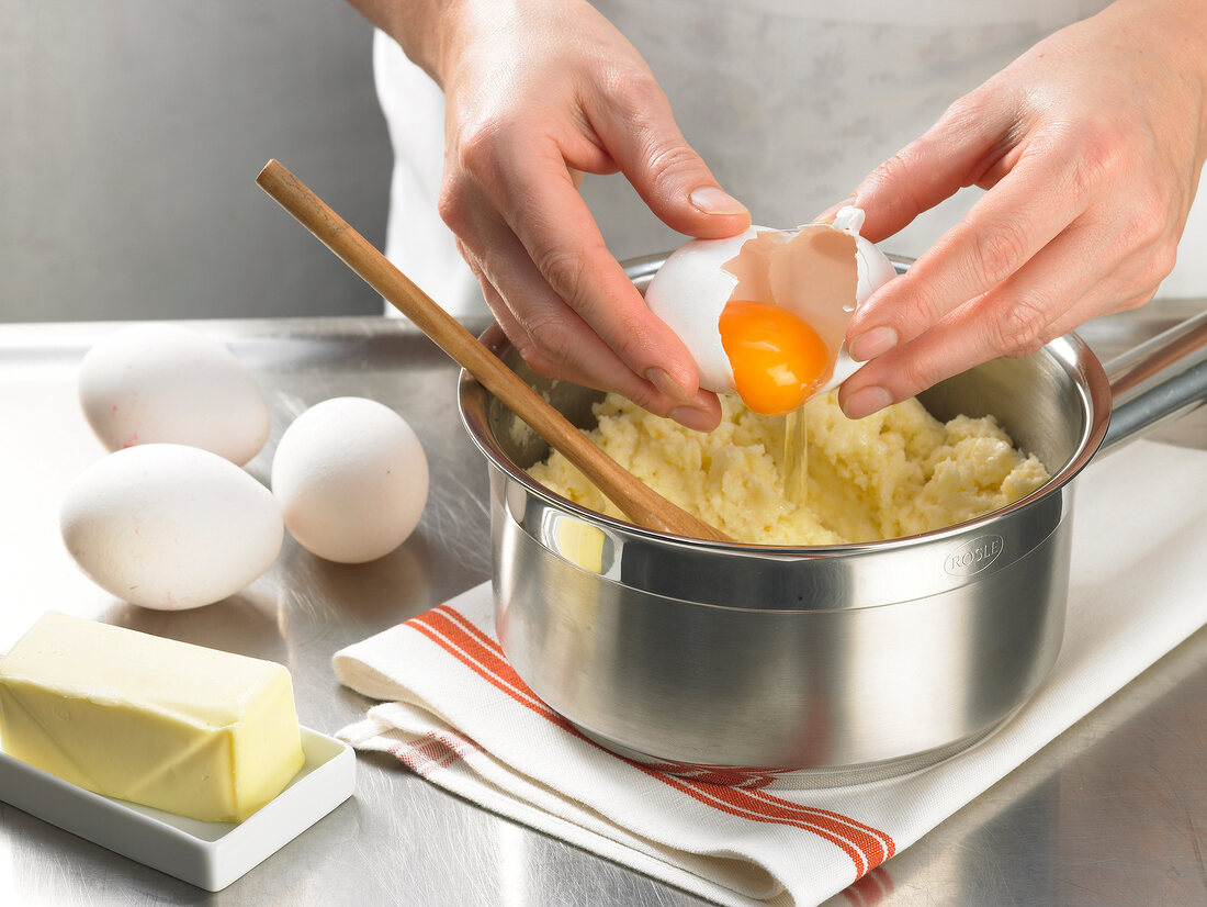 Adding egg to dough in saucepan, step 1