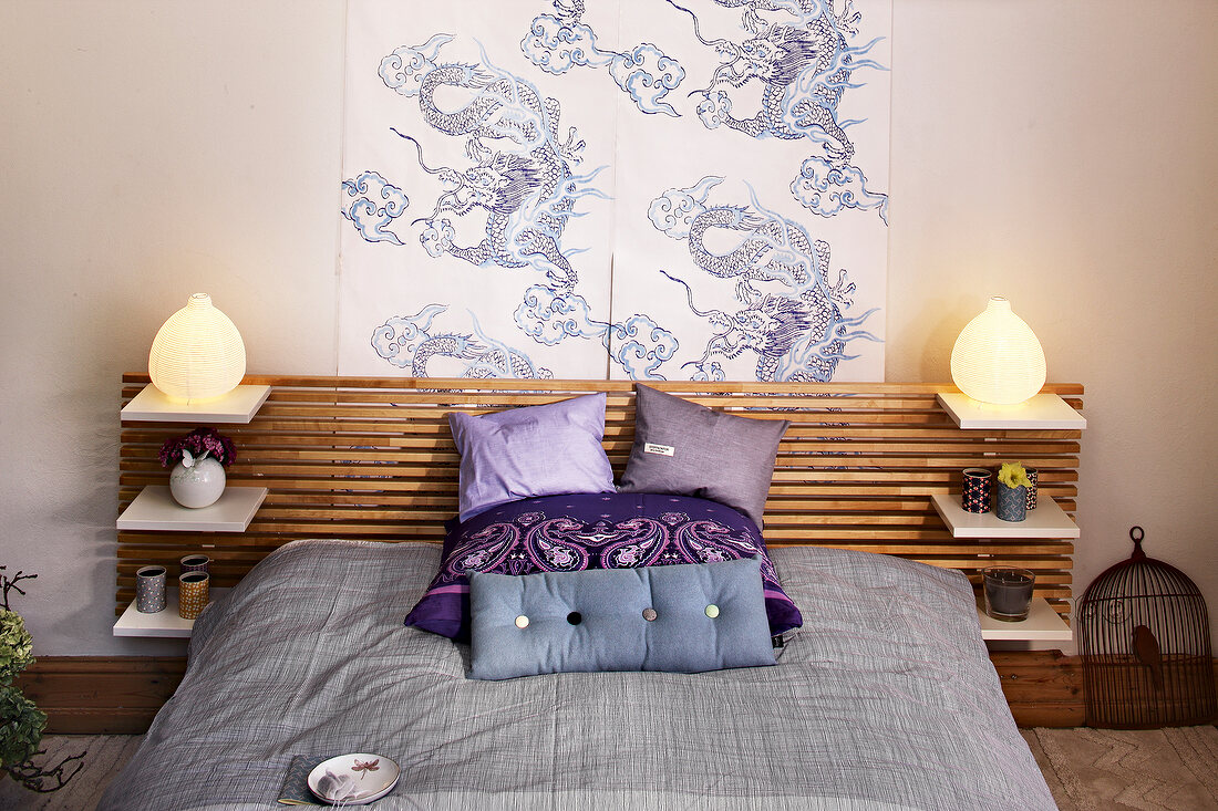 Modern bed with asian style headboard, cushions and illuminated lamps on either side
