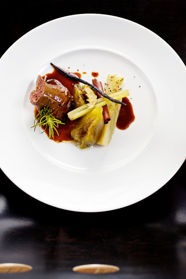 Glazed lamb liver with fennel and fig stew on plate on black background