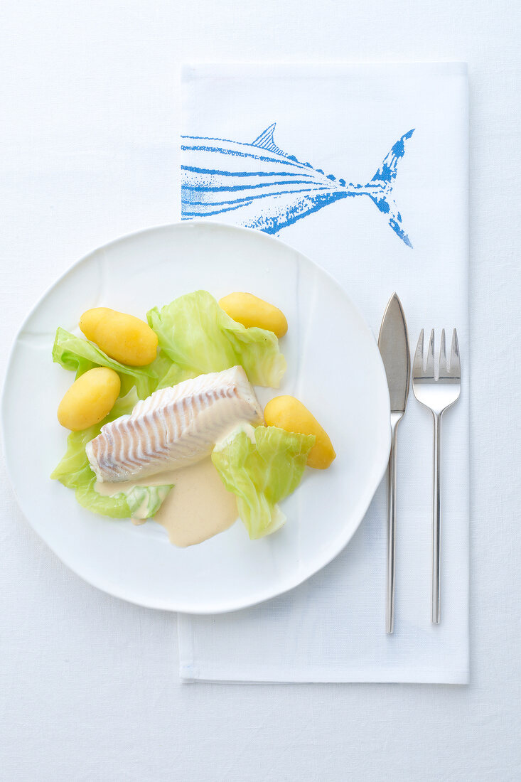 Haddock with mustard sauce, cabbage and potatoes on plate, overhead view