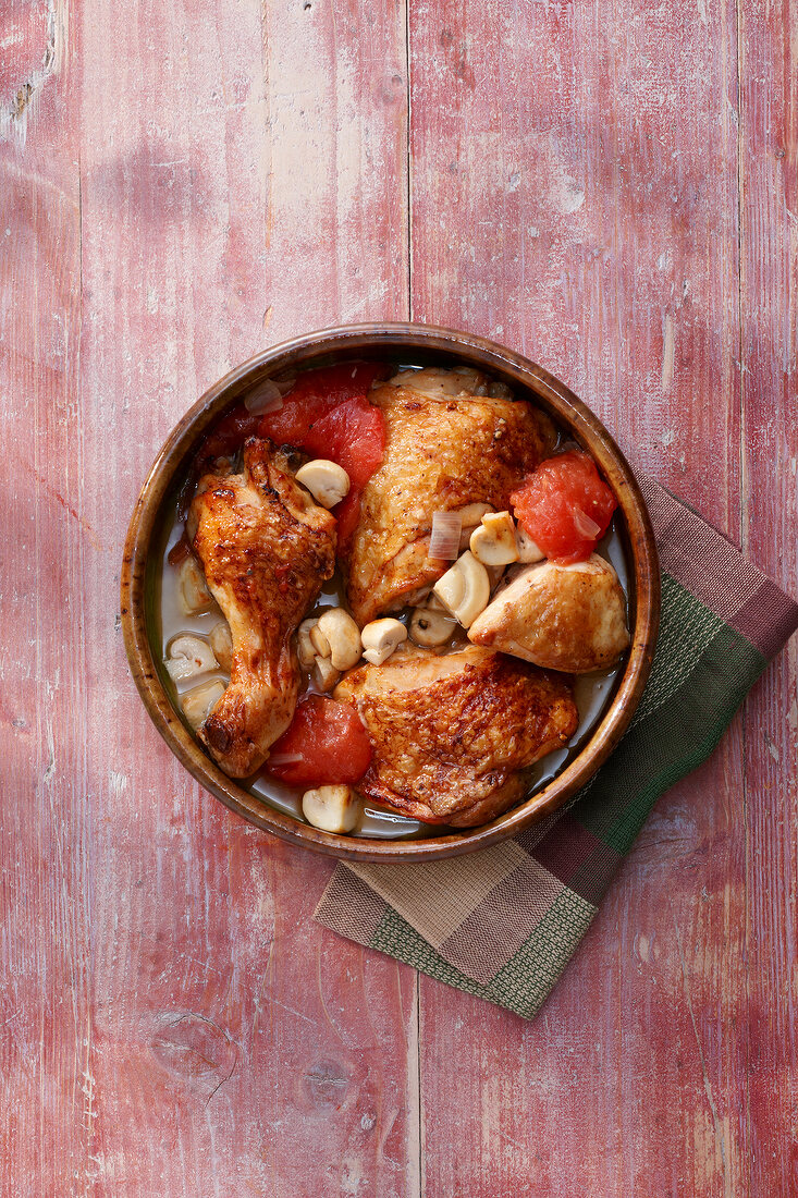 Vinegar Chicken with mushrooms and tomatoes in bowl, overhead view
