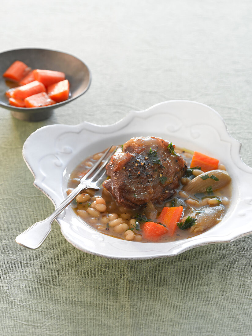 Veal cheeks with white beans and glazed carrots in serving dish