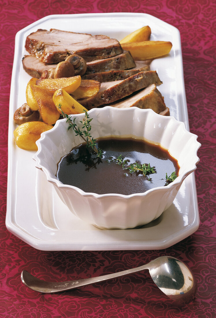 Sliced pork served with root beer-cumin sauce on plate