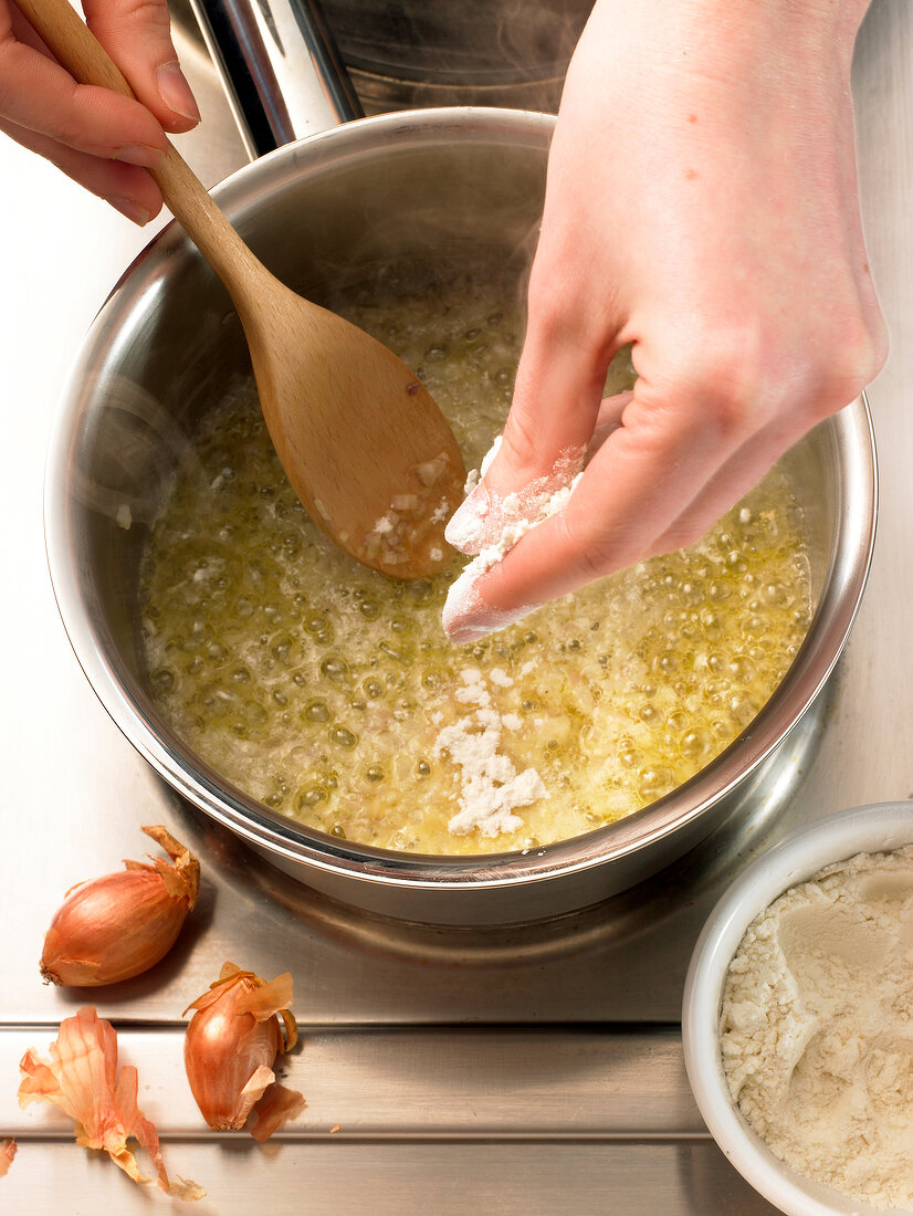 Adding flour to mixture in saucepan while preparing mustard sauce, step 1