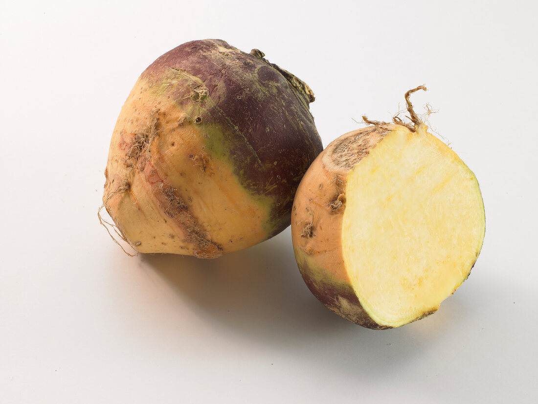 Whole and half turnip on white background