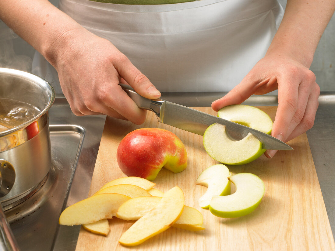Apple being cut into slices with knife for preparation of apple soup, step 1