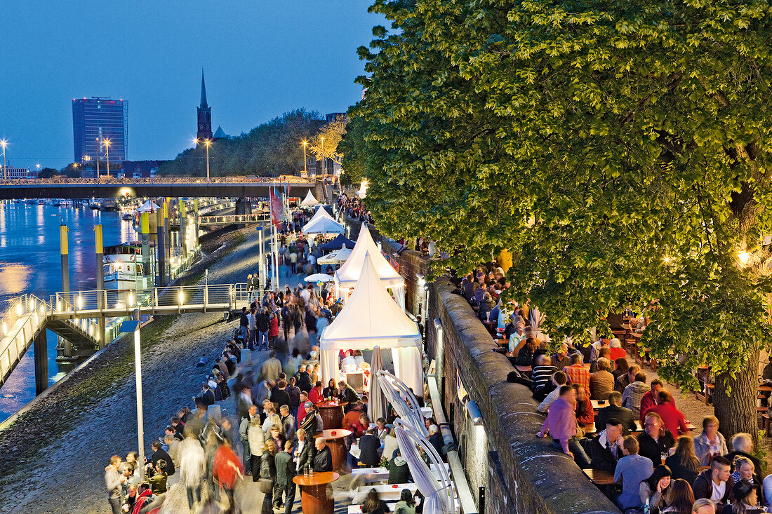 People enjoying festival in harbour side at dusk, Bremen, Germany