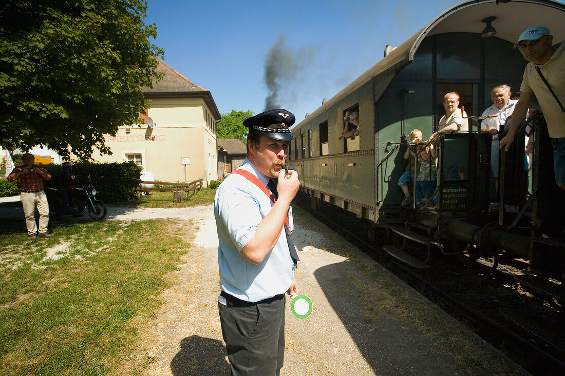 People on train and station master whistling in Franconian Switzerland, Bavaria, Germany