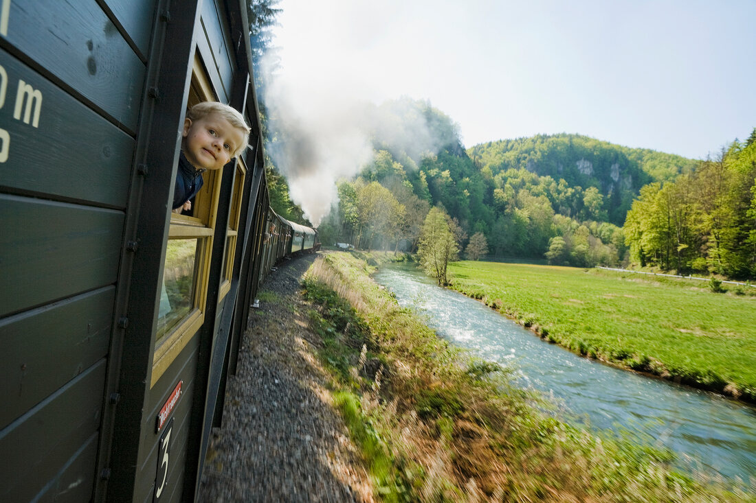 Boy peeping out of moving train in Franconian Switzerland, Bavaria, Germany