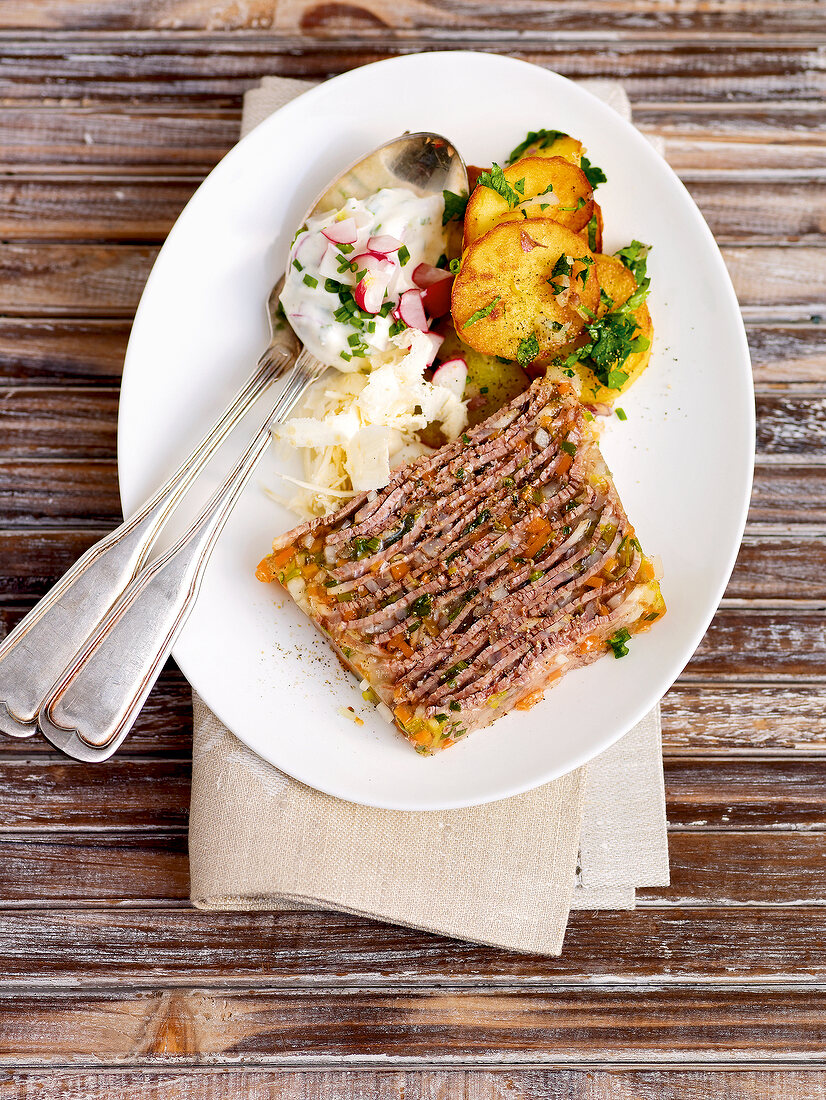 Jellied beef with roast potatoes and horseradish sauce on plate