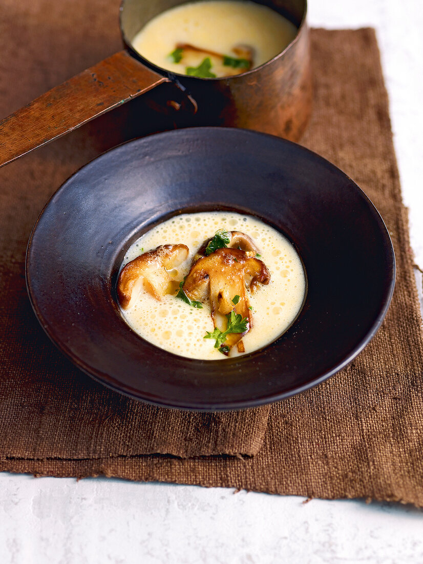 Potato soup with fried mushrooms in bowl on brown napkin