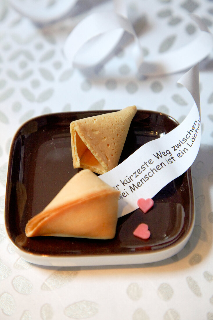 Two fortune cookies on brown plate