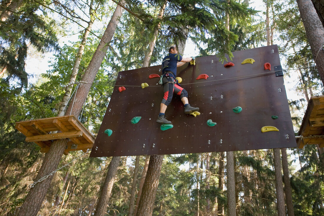 Man wall climbing in woods in Nature Park, Franconian Switzerland, Bavaria, Germany