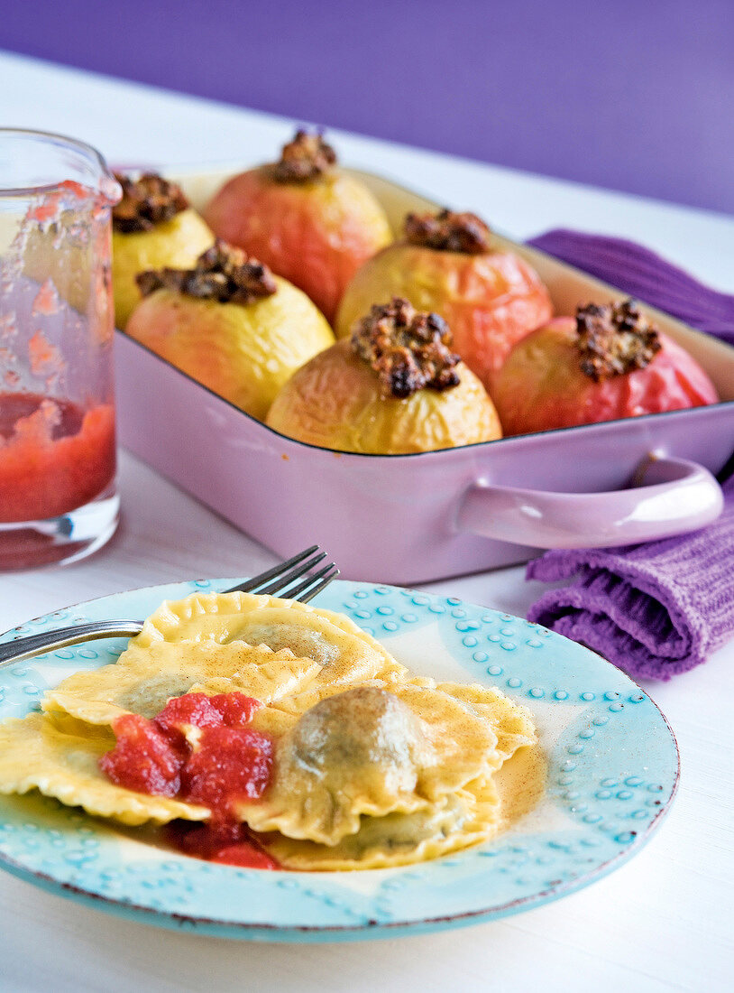 Close-up of sweet poppy ravioli on plate and baked apples in baking dish