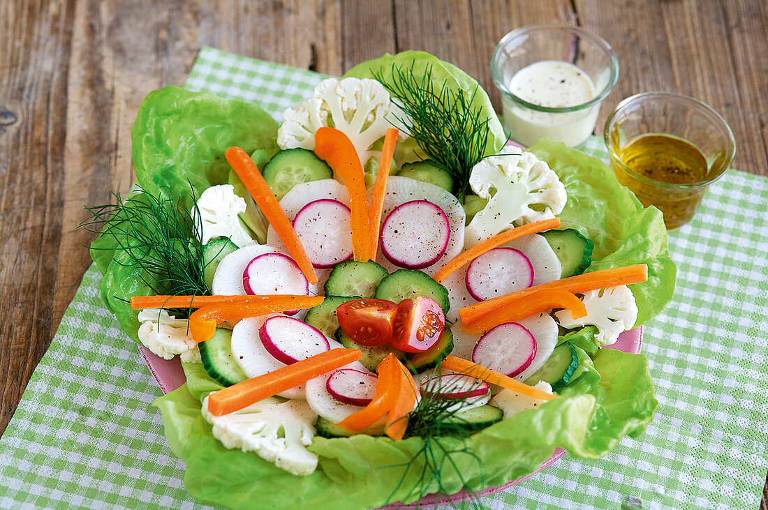 Flowery crudites with two dressings in glass on checked tablecloth