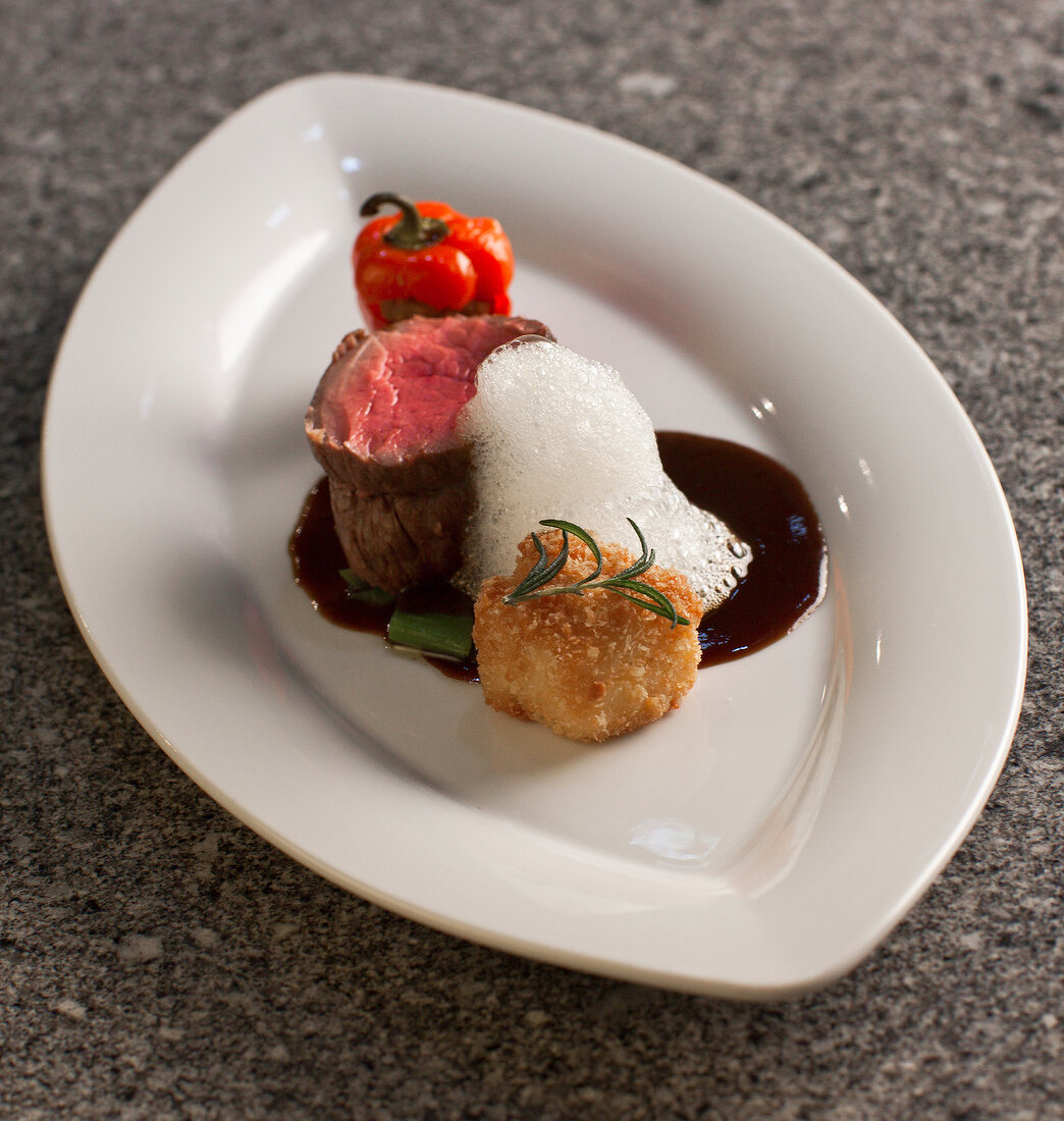 Rinderfilet, mit Hack gefüllte Paprika und Maiskroketten auf Teller