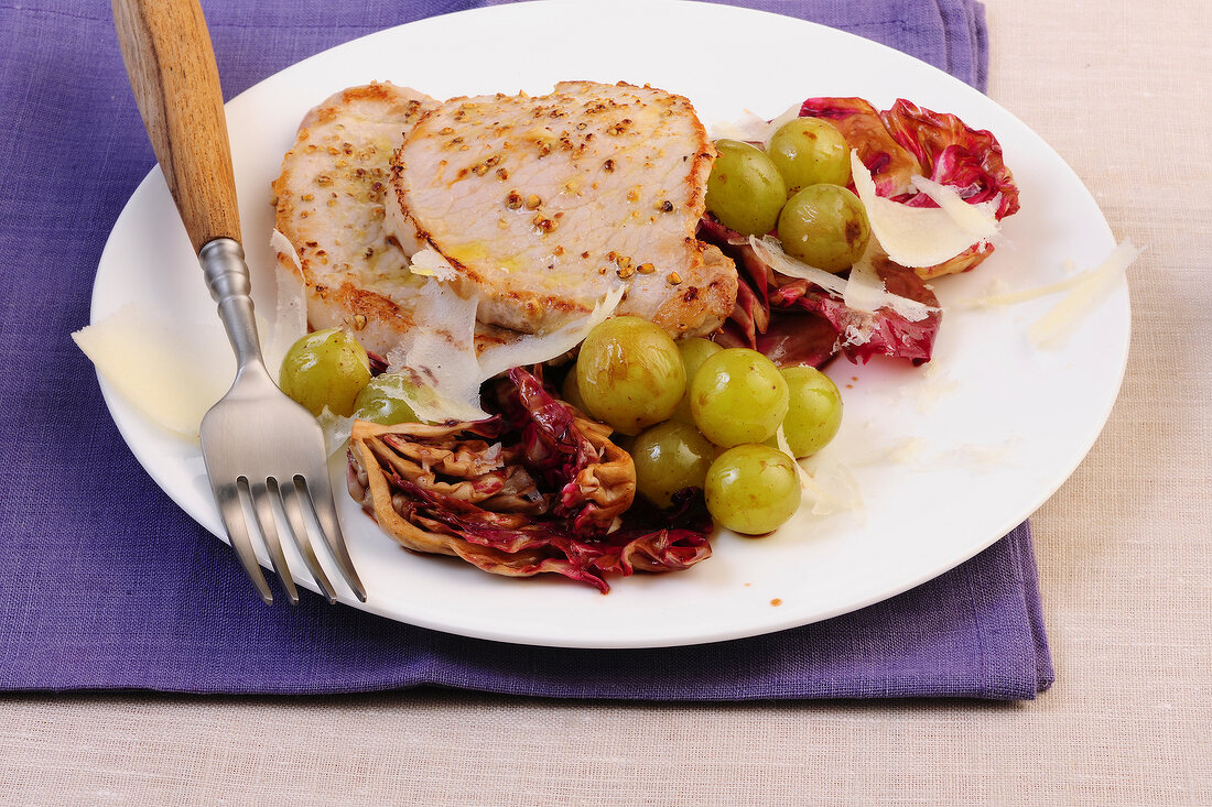 Steak with radicchio and grapes on plate with fork