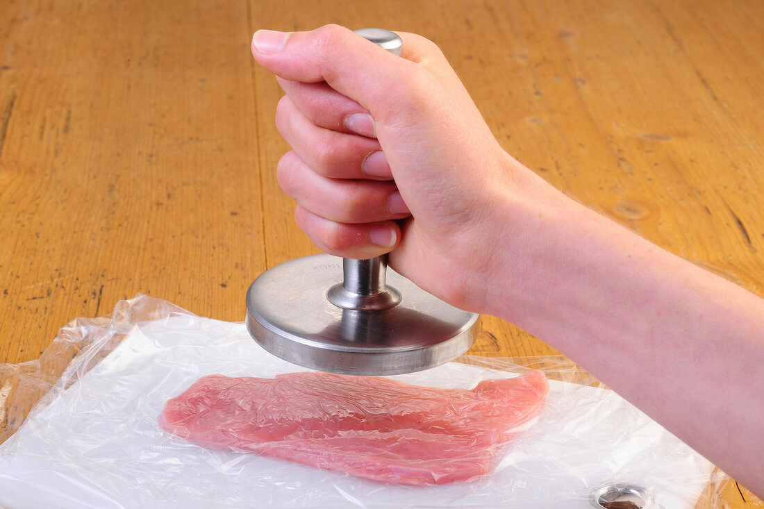 Meat being flattened with meat tenderizer, step 1