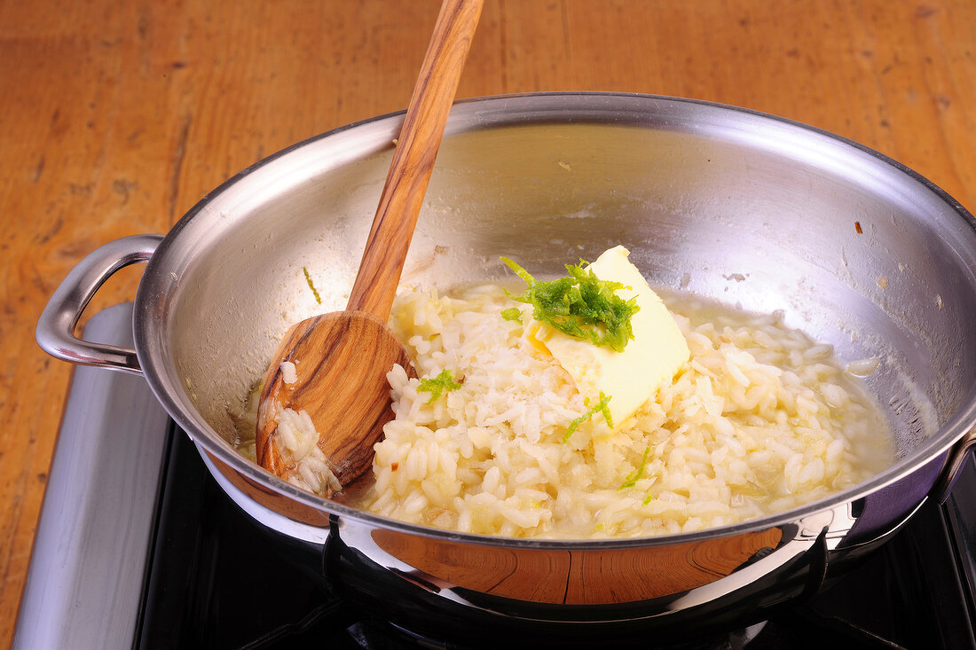 Stirring risotto rice with butter and lime in wok, step 3