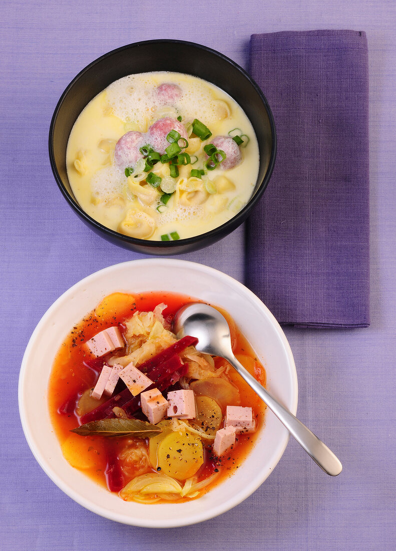 Cheese soup with tortellini and borsch soup with meat loaf in bowls