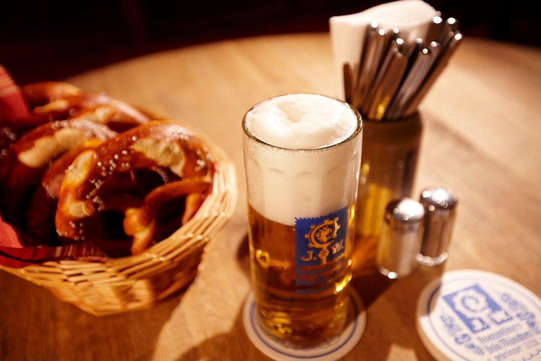 Basket of pretzels and beer glass on wooden table