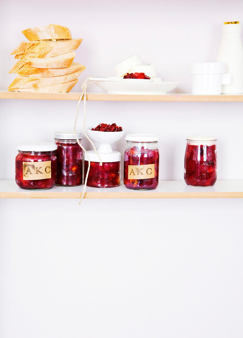 Apricot and cherry chutney in jar with bread on the shelf