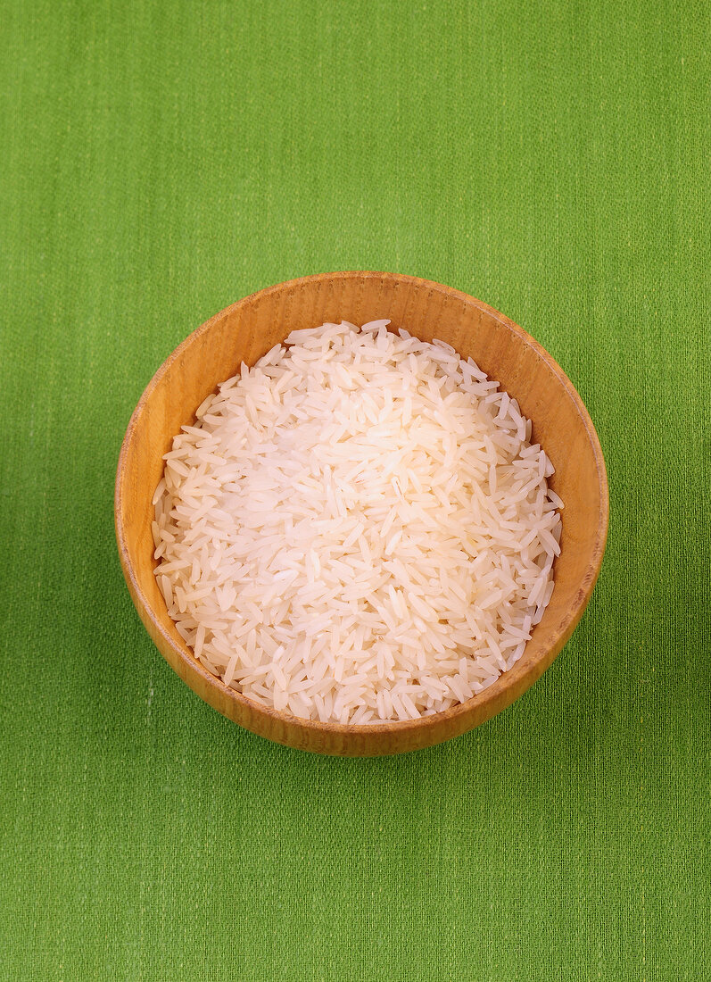 Basmati rice in bowl on green background