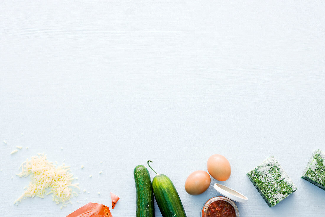 Cheese, cucumber, eggs and spinach on white background