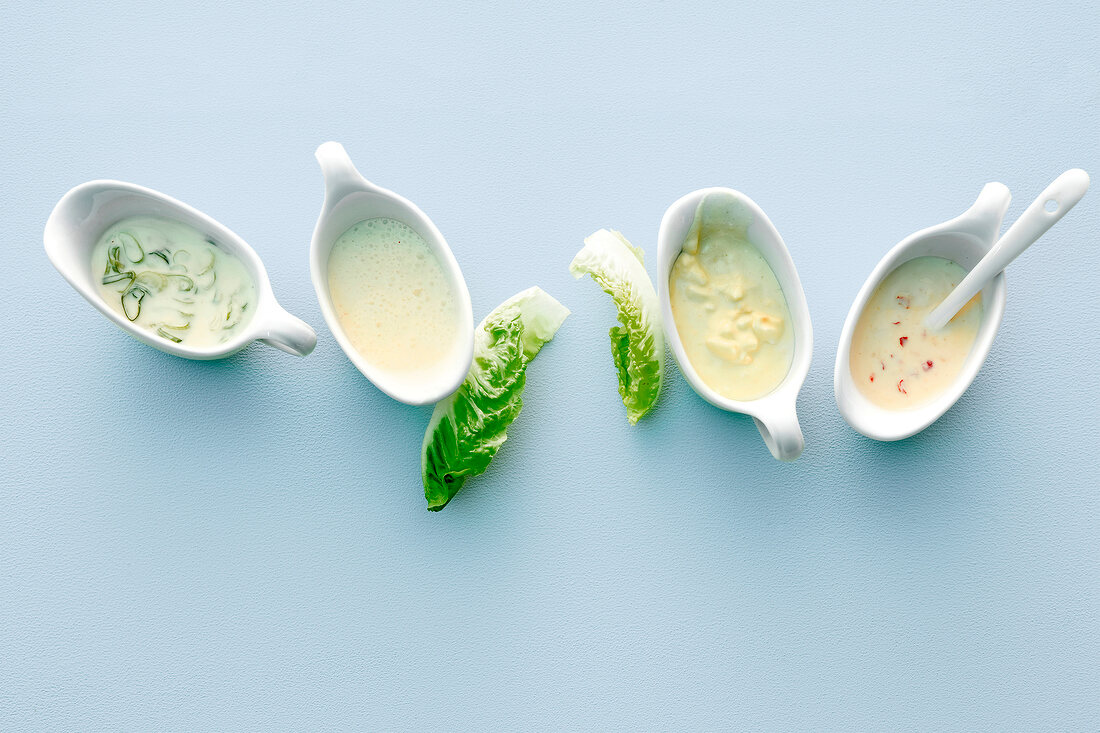 Four different salad dressings in sauceboats, overhead view