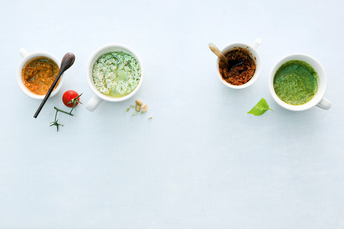 Four different sauces for pasta in cups, overhead view