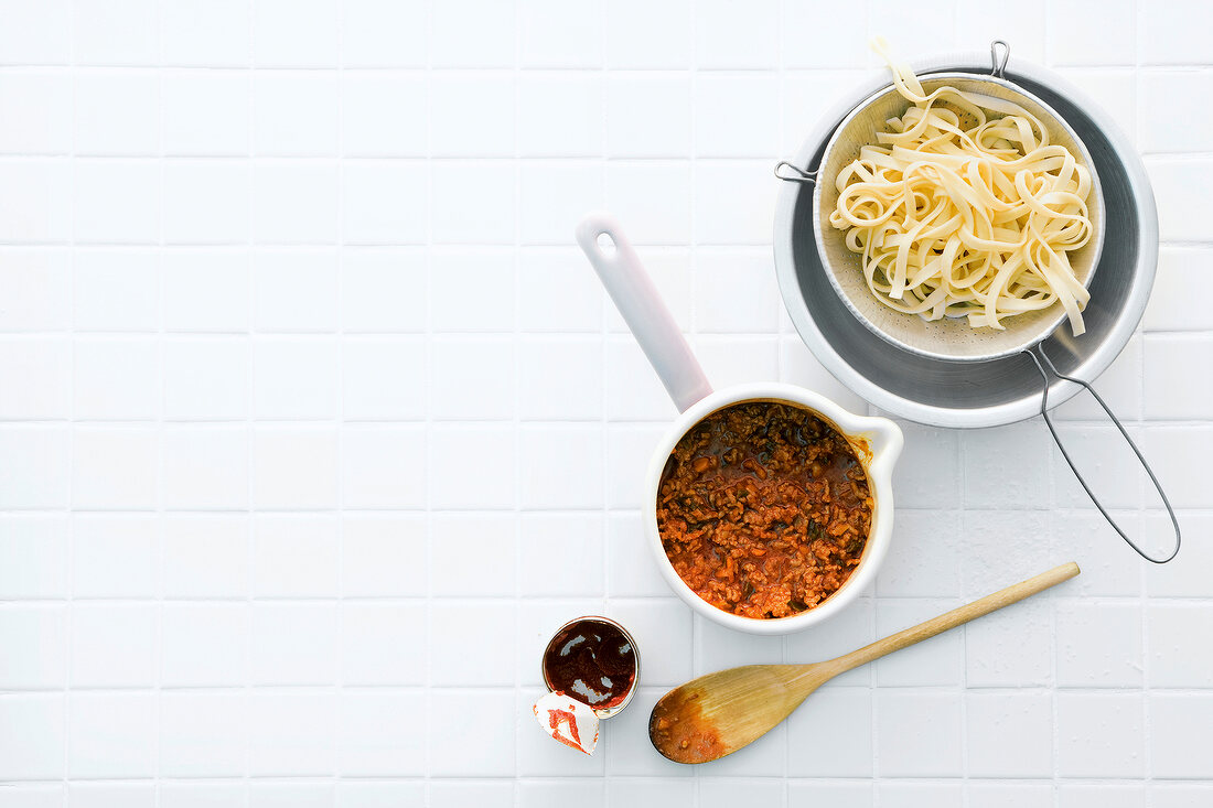 Ribbon pasta and Bolognese sauce in pan on white background