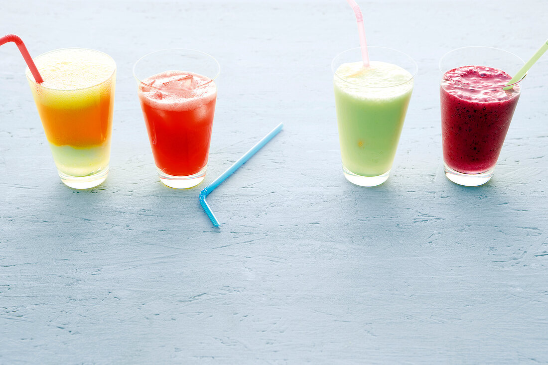 Four mocktails in glasses with straws