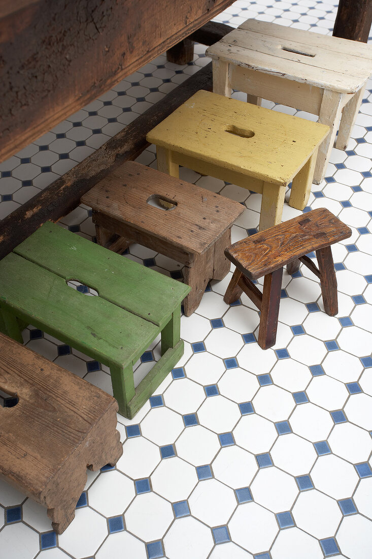 Various old stool and ottoman on white checked floor