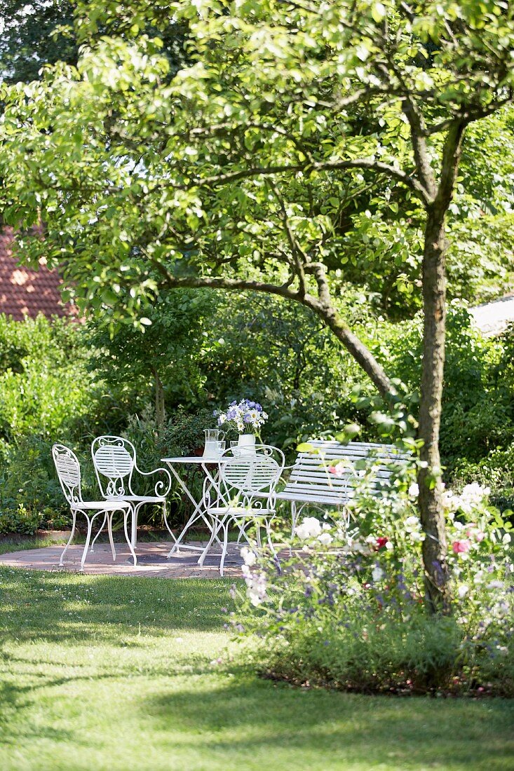 Bistro furniture in seating area in shade of wild cherry in garden