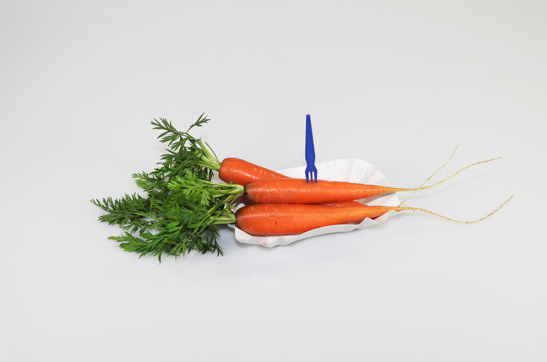 Carrots in paper dish on white background