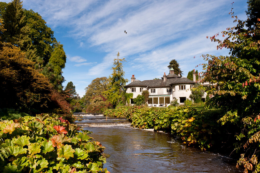 View of Mount Usher garden and mansion near water in Ashford, Ireland