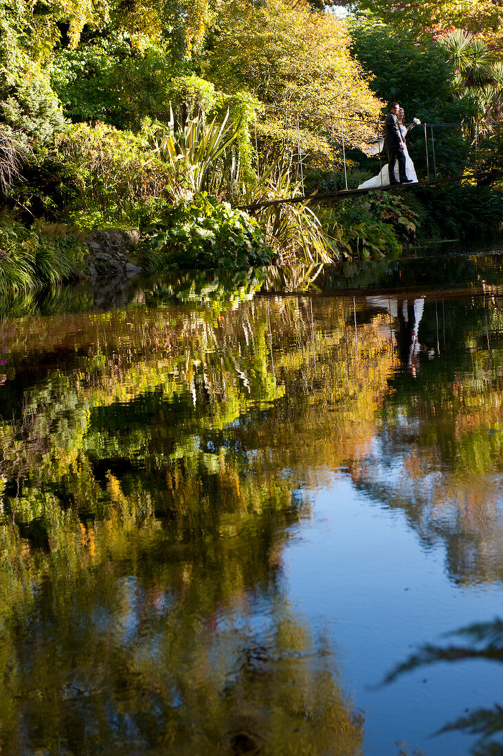 Couple standing at Mount Usher Garden bridge, Ashford, Ireland, UK