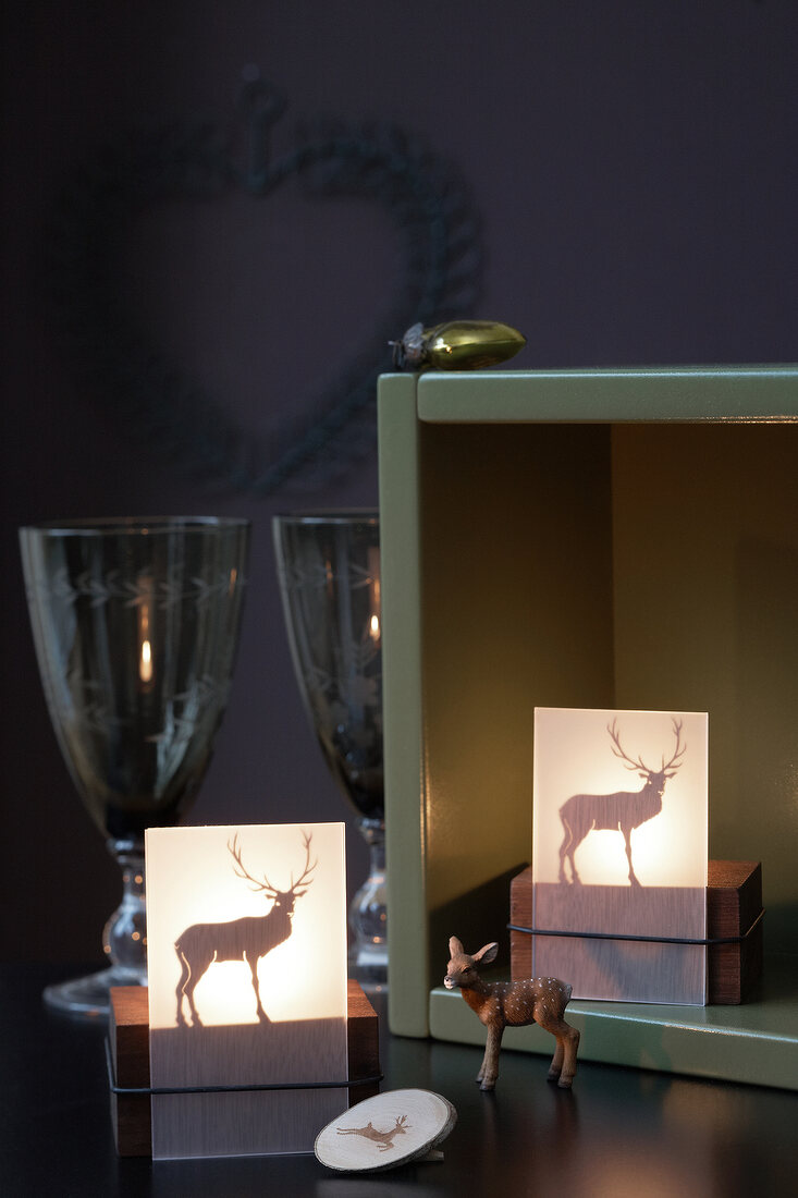 Illuminated lanterns with deer motifs and deer figurine in front