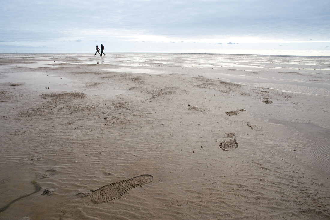 Two people running on beach of Wadden Sea, Germany