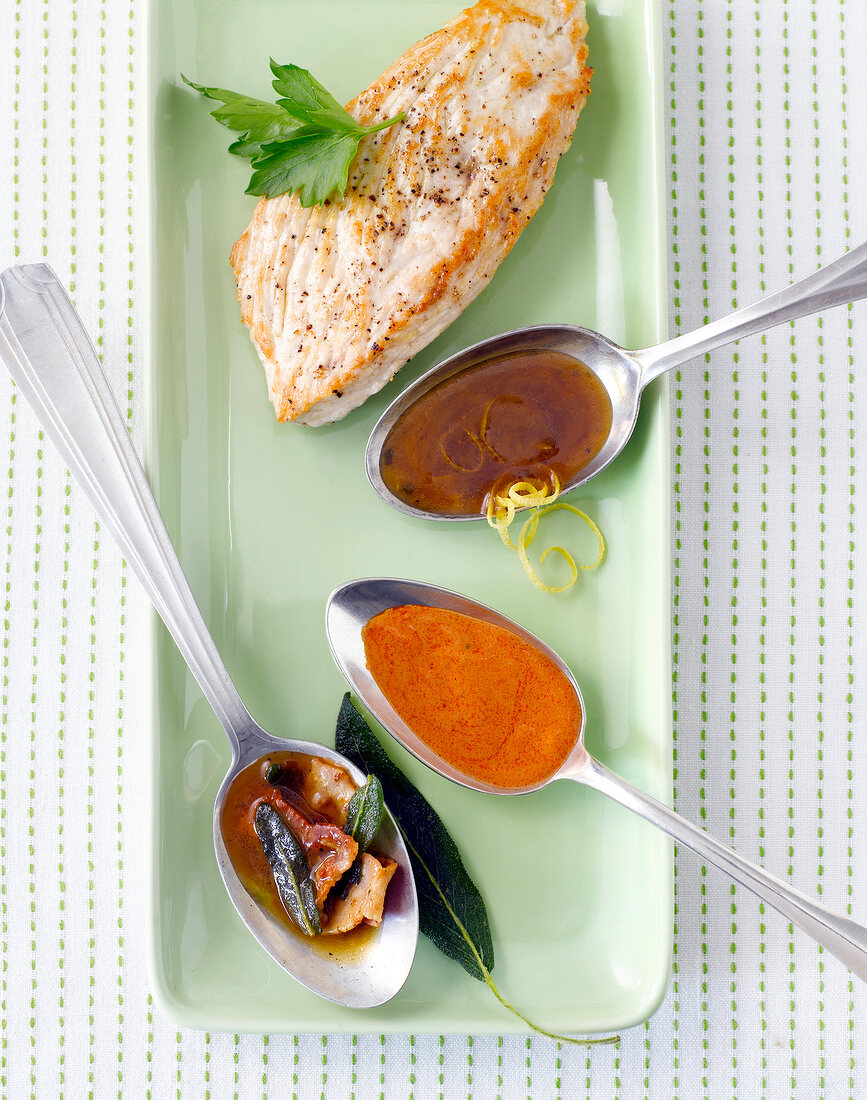 Schnitzel with spoons of three different sauces in tray