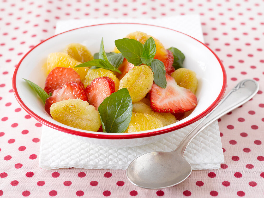 Sweet gnocchi with oranges and strawberries in bowl