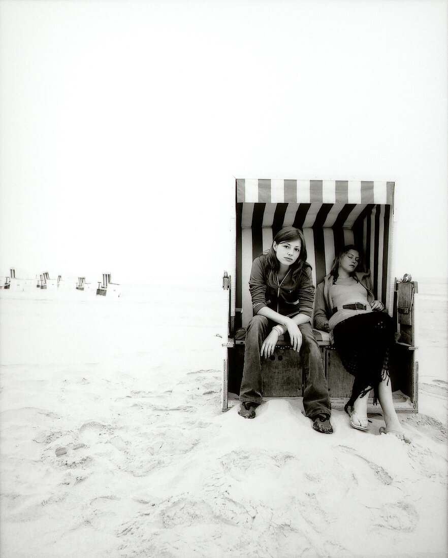 Two woman sitting in beach chair on West beach in Sylt, Germany, black and white