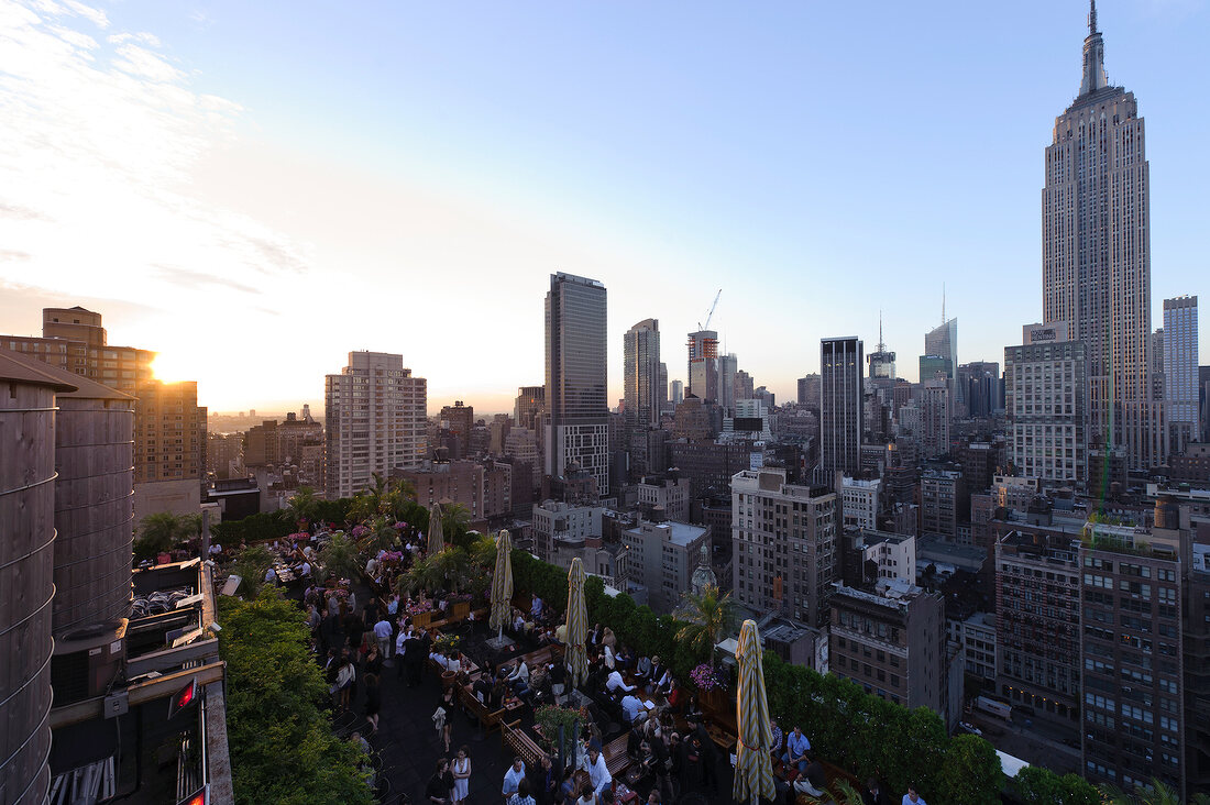 View of cityscape overlooking people sitting on rooftop bar at New York, USA