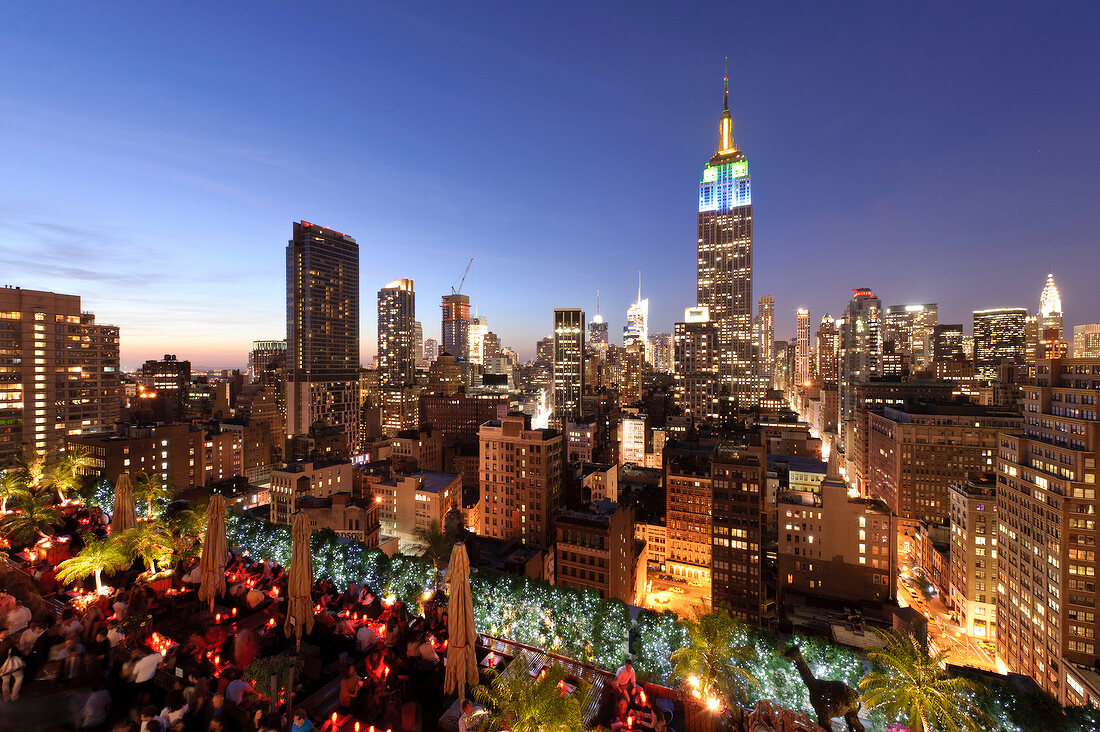 View of cityscape overlooking people sitting on rooftop bar at New York, USA