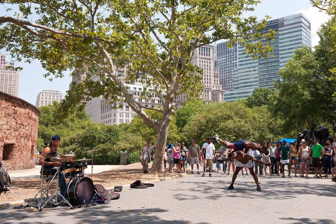 Crowd watching street musicians and dancers perform at Battery Park, New York, USA