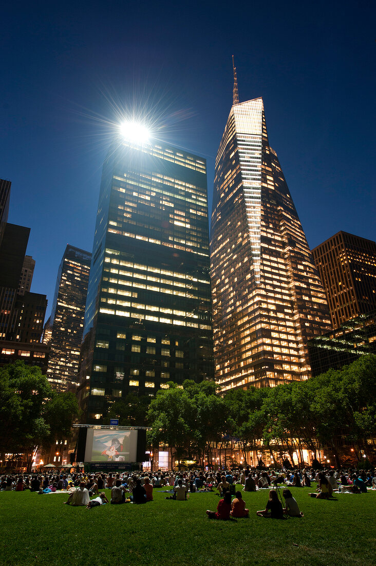 People sitting in meadow and watching movie at Bryant Park, New York, USA