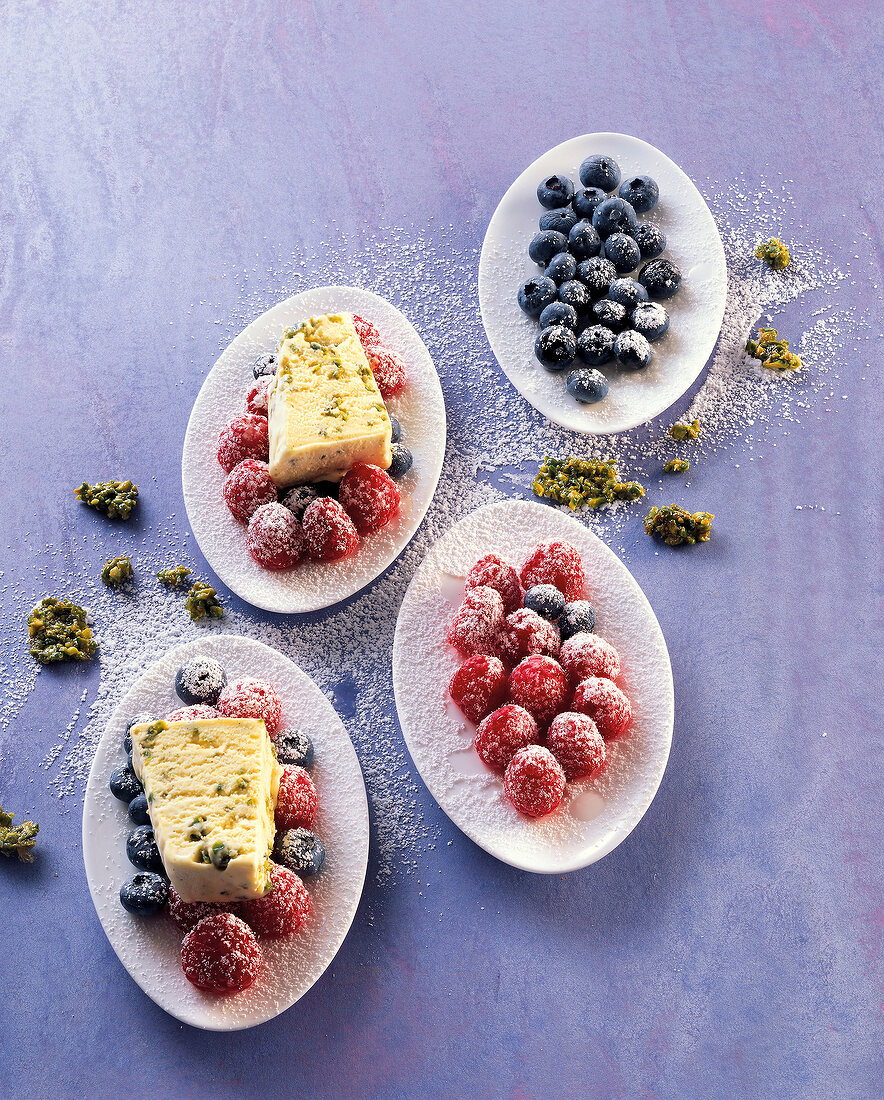 Ice cream with rose oil, pistachios and berries on plates